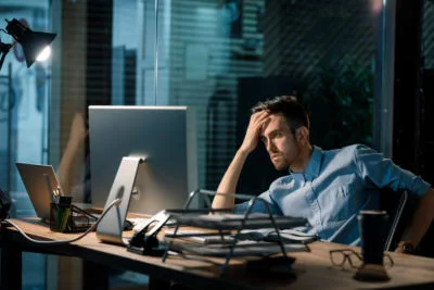 Man Sitting Alone In Office Late At Night Watching Computer