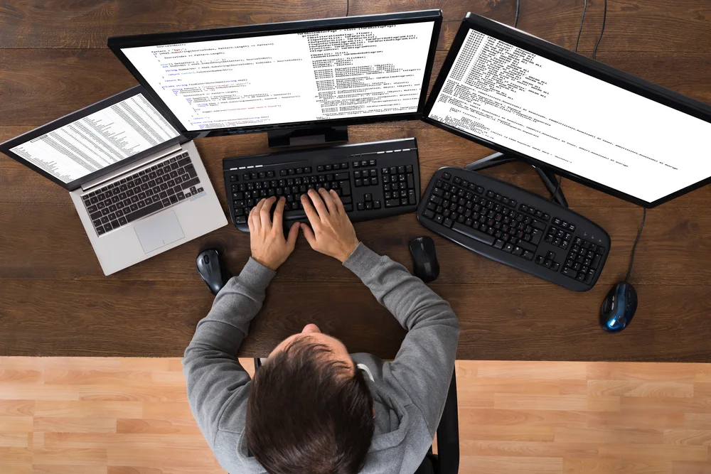 A person working on 3 different computers